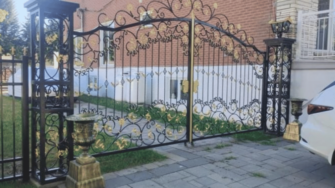 A bi-parting wrought iron gate splits a twenty foot opening into two manageable halves